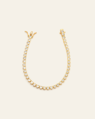 hero image of 14k gold vermeil 3mm clear CZ heart tennis bracelet on cream background.