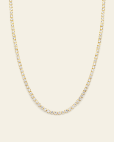 A Gold Vermeil bezel set tennis necklace with CZ stones displayed on a cream background.