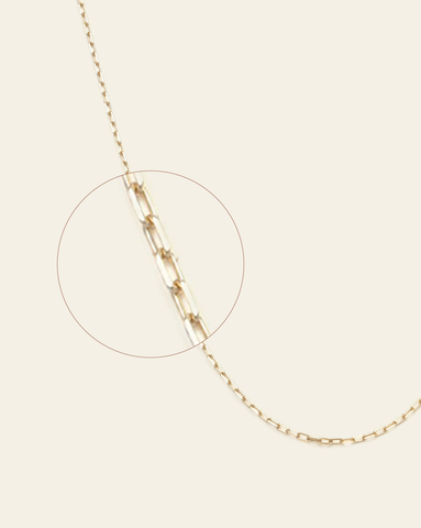 A magnified close up of solid gold delicate staple chain.