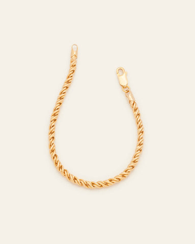 A Gold Vermeil thick rope bracelet with a luxe twisted, textured design featuring a lobster clasp on a cream background.