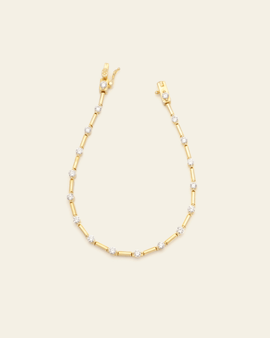 A photo of a Gold Vermeil modern tennis bracelet with a sleek design, featuring alternating sparkling CZ stones and gold metal links, shown with an open box clasp, against a cream background.