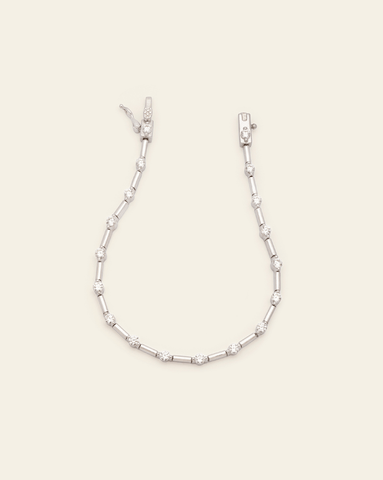 A photo of a Sterling Silver modern tennis bracelet with a sleek design, featuring alternating sparkling CZ stones and gold metal links, shown with an open box clasp, against a cream background.