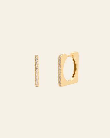 A photo of a pair of rectangular Gold Vermeil huggies with pave CZ stones along each side, against a cream background. 