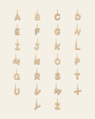 hero image of gold vermeil pave puffed letter pendants A-Z on cream background. 