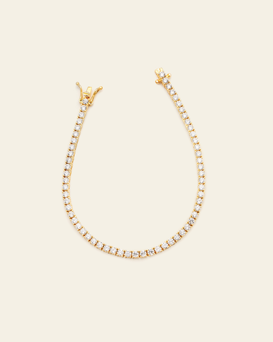 A Gold Vermeil prong set tennis bracelet with CZ stones and an open box clasp displayed on a cream background.