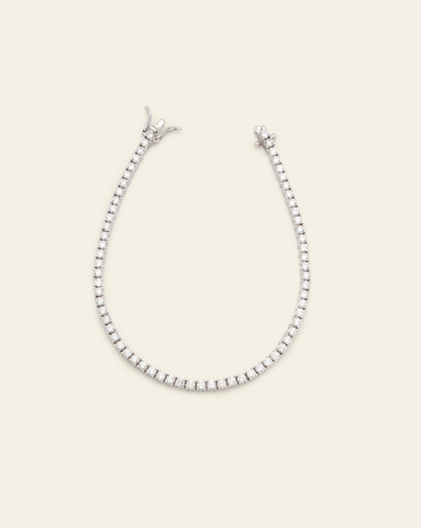 Sterling silver tennis bracelet featuring prong-set sparkling cubic zirconia stones on a cream background.