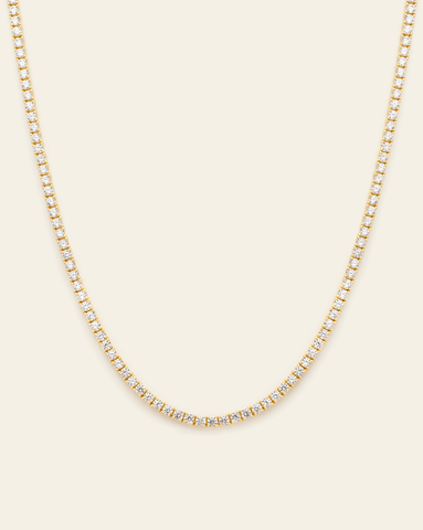 A Gold Vermeil prong set tennis necklace with CZ stones displayed on a cream background.