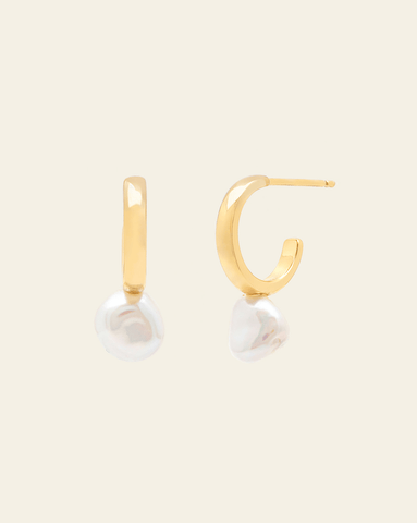 A pair of Gold Vermeil hoop stud earrings featuring small baroque pearls attached to the bottom of the hoops, on a cream background.