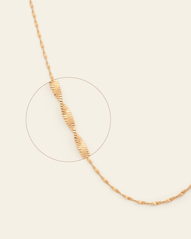 A magnified image of Gold Vermeil Singapore chain with a twisted, textured design on a cream background.