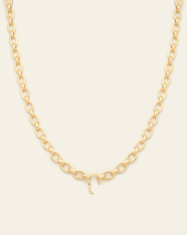  Gold-plated chain necklace displayed against a light beige background, featuring medium-sized oval links and a small, elegant clasp detail at the center.