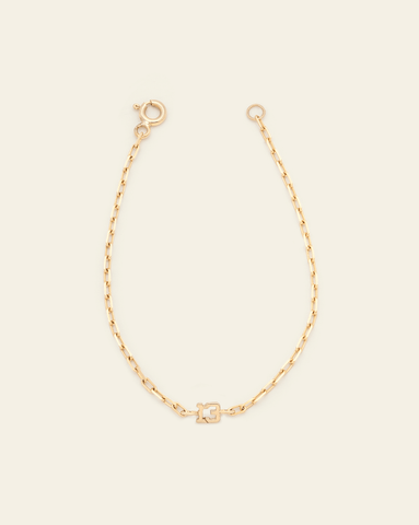 A photo of a Solid Yellow Gold thin staple chain bracelet with the number 13 in the centre against a cream background. 