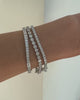 A close-up video of a model’s wrist showcasing three sterling silver tennis bracelets layered together, two with bezel-set cubic zirconia stones and one with prong-set cubic zirconia stones, highlighting their open box clasps.